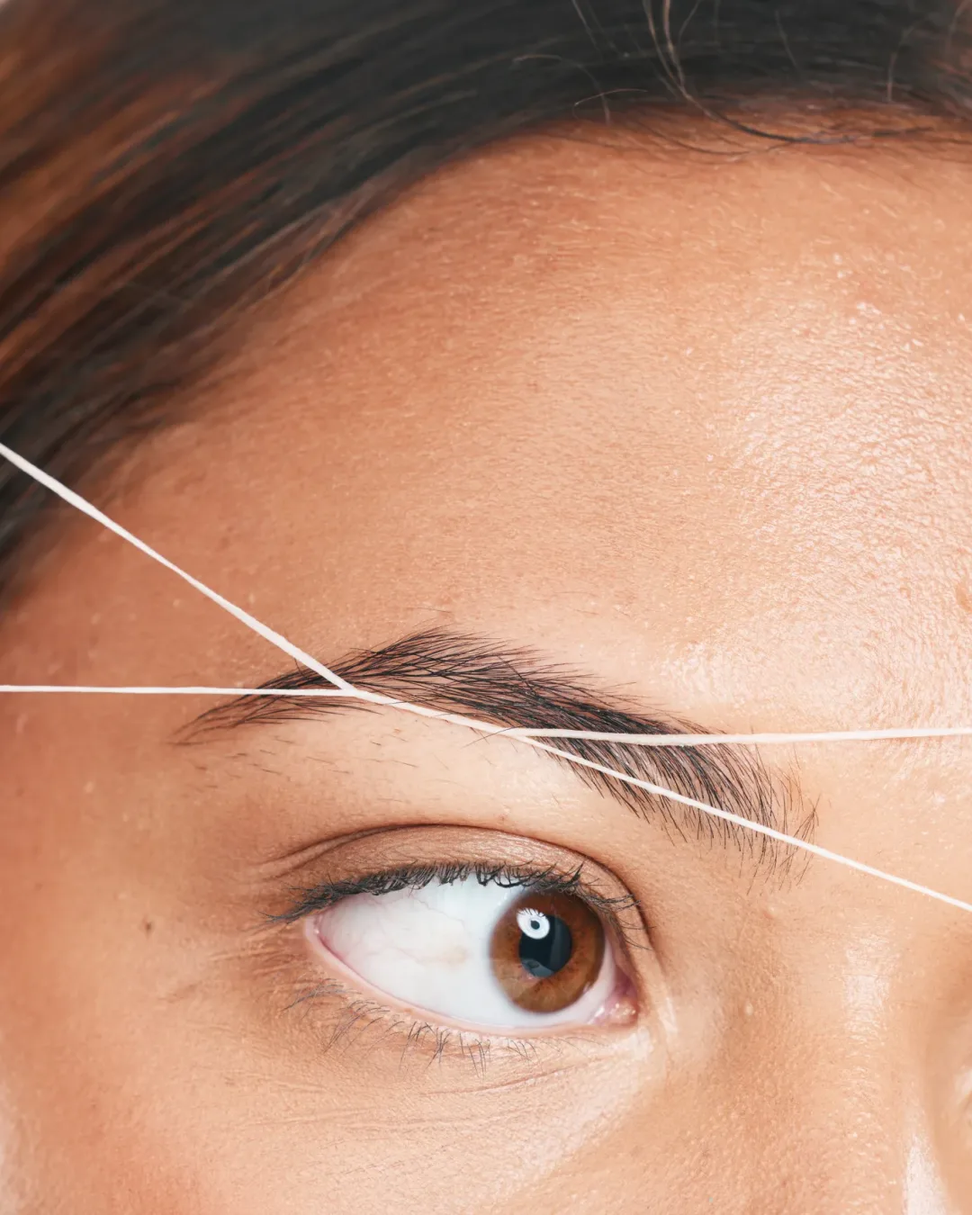 Threading, eyebrows and beauty with a model black woman in studio on a beige background for hair removal. Eyes, zoom and wellness with an attractive young female using a product on her face.